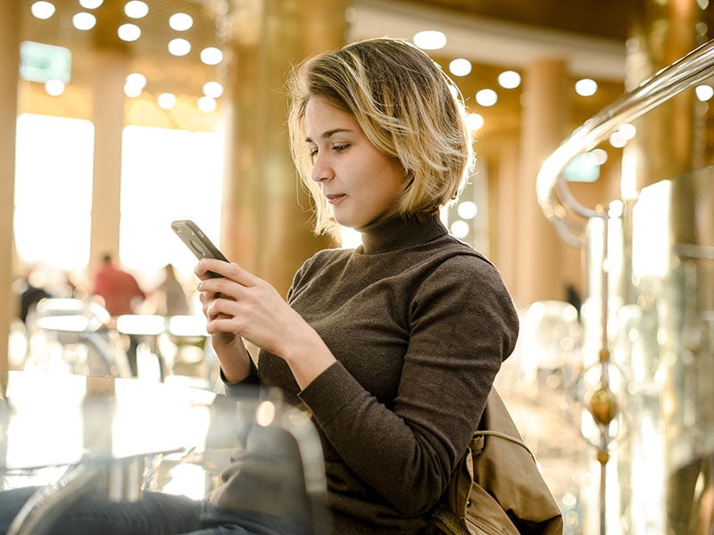 young-european-girl-is-chatting-online-by-phone-in-a-cafe-mall